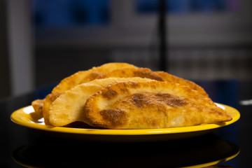 Several fried appetizing pasties lie on a yellow plate on the table
