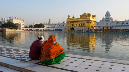 wide shot of two sikh worshipers at the golden temple in amritsar