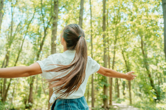 Happy woman in forest with open arms from behind breathing clean air. Environment, no pollution healthy natural living lifestyle. Free spirit in the woods.