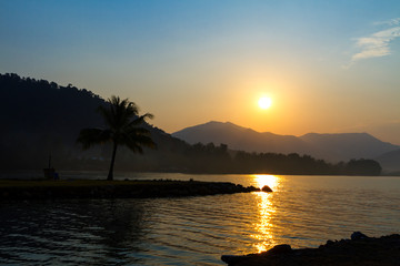 Fototapeta na wymiar Sunrise with silhouette coconut on the beach