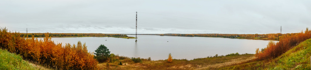 Beautiful lake and yellow trees in autumn cloudy day. Panoramic landscape.