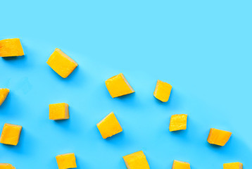 Sliced ripe mango cubes on blue background.