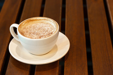 A white cup of coffee on wooden background, copy space