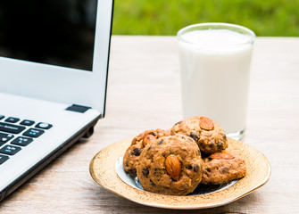A glass of milk and cookies with laptop on the table , out door   Chiangmai  Thailand.