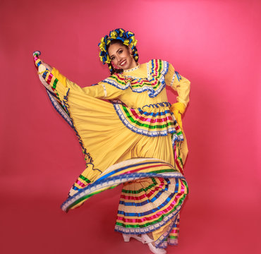 Bailarina vestida en traje tradicional folclórico mexicano amarillo en fondo rosa retrato