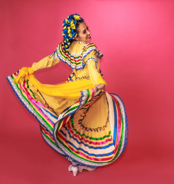 Bailarina vestida en traje tradicional folclórico mexicano amarillo en fondo rosa retrato