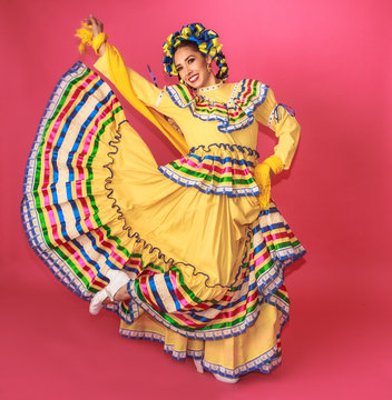 Bailarina vestida en traje tradicional folclórico mexicano amarillo en fondo rosa retrato
