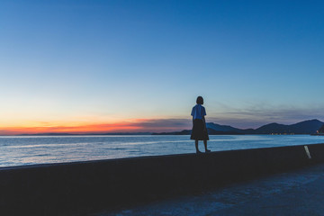 夕暮れの海にいる女子高生