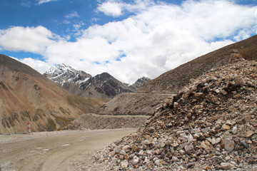 View of mountains and dirt road with the dramatic sky in Tibet, China