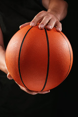 Hands of basketball player with ball on dark background