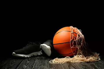 Poster Ball for playing basketball, shoes and net on table against dark background © Pixel-Shot