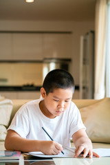 Naklejka premium Asian boy doing his homework at home