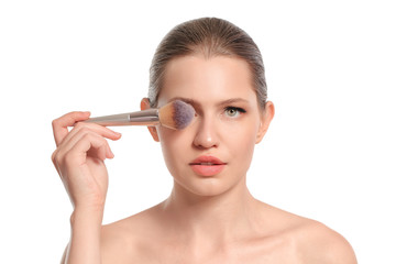Fototapeta premium Beautiful young woman with makeup brush on white background
