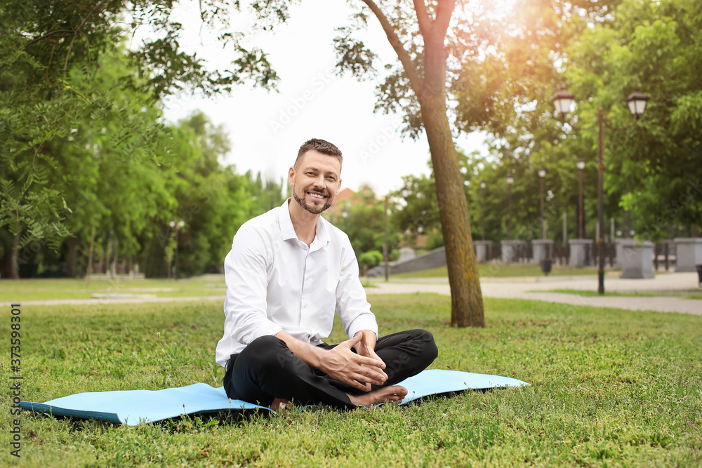 Sticker Handsome businessman meditating in park