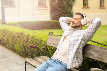 Handsome man listening to music while relaxing in park