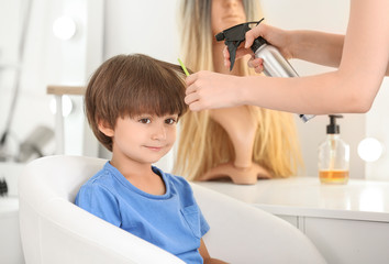 Female hairdresser working with little boy in salon