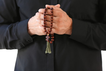 Male praying priest with rosary beads, closeup
