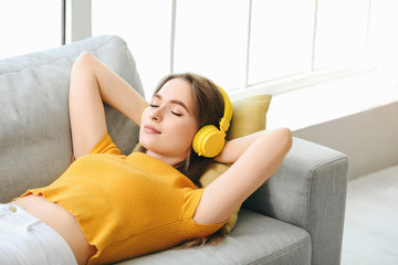 Sleepy young woman listening to music at home