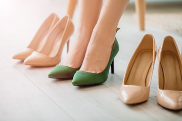 Young woman trying on different shoes at home