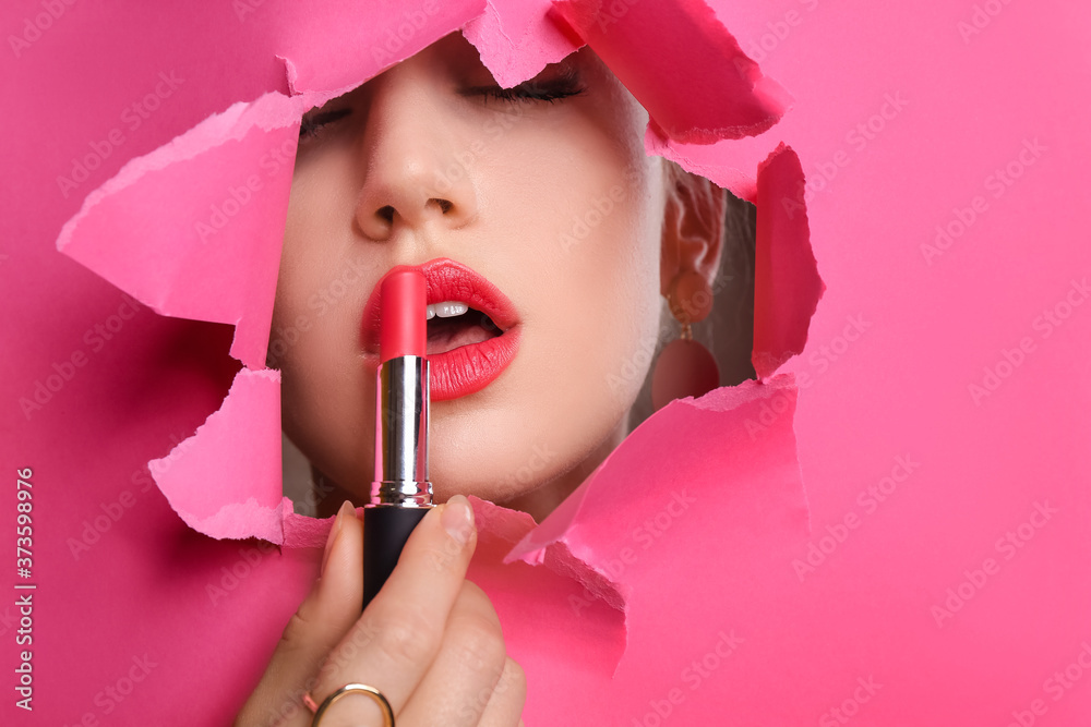 Poster Beautiful young woman with bright lipstick visible through hole in color paper