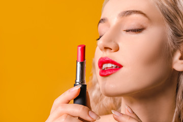 Beautiful young woman with bright lipstick on color background