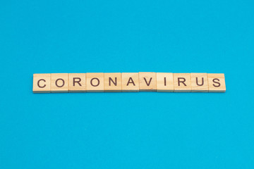 Word CORONAVIRUS made from wooden cubes on blue background