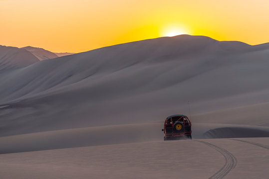 Silhouette of a buggy driving in the coastal peruvian desert at sunset between Ica and Huacachina, Peru.