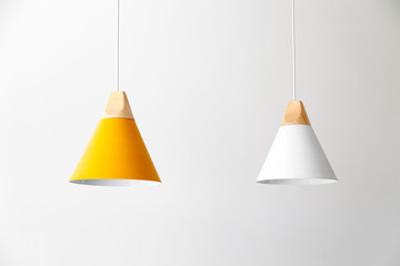 White and yellow lamps with light wooden parts are hanging on the cables