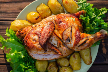 Grilled chicken with potatoes, salad and parsley on a white plate
