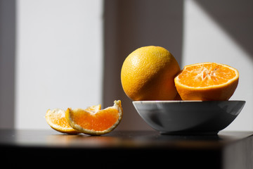 Oranges for breakfast. Healthy fruit in a plate on a table with sunshine