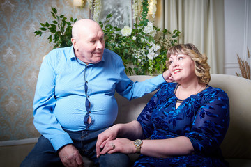 Portrait of an elderly bald man and fat plump woman in a blue dress in a nice room. Old pensioner...