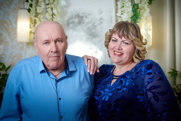 Portrait of an elderly bald man and fat plump woman in a blue dress in a nice room. Old pensioner...