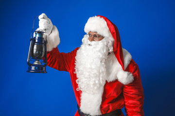 African-American Santa Claus with lantern on color background