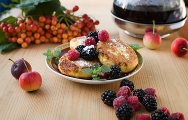 Cheesecakes. Cheese pancakes and tea. fresh berries, little apples. Syrniki for breakfast.