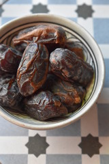 Dates in a bowl on ethnic mosaic tile. Ramadan kareem.