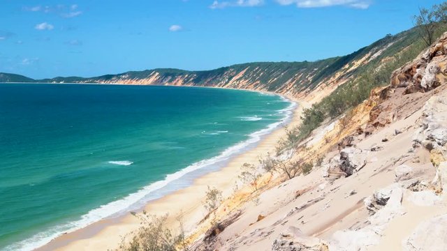 Scenic landscape view of peaceful sandblow at Cooloola, green ocean sea water at beautiful Rainbow sandy beach on bright blue sunny sky day, Queensland, Australia, static