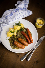 Oldenburger Grünkohl mit Pinkel, Kohlwurst, Senf und Kartoffeln auf Holz Tisch