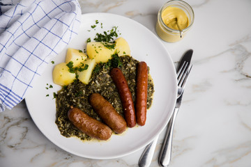 Oldenburger Grünkohl mit Pinkel, Kohlwurst, Senf und Kartoffeln auf Marmor Tisch