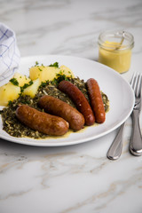 Oldenburger Grünkohl mit Pinkel, Kohlwurst, Senf und Kartoffeln auf Marmor Tisch