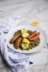 Oldenburger Grünkohl mit Pinkel, Kohlwurst, Senf und Kartoffeln auf Marmor Tisch