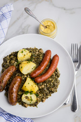Oldenburger Grünkohl mit Pinkel, Kohlwurst, Senf und Kartoffeln auf Marmor Tisch