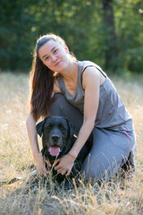 Young attractive sport girl with black Labrador in park. Healthy lifestyle. Walk with favorite pet in wood.