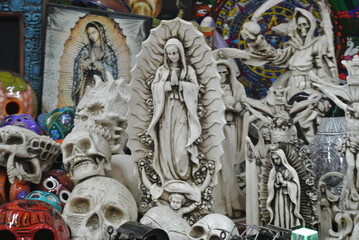 Statue of the Virgin Mary along with skull and other carvings in a souvenir shop in mexico