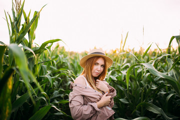 a girl in a straw hat in a cornfield