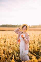 a girl in a straw hat in a field with an apple