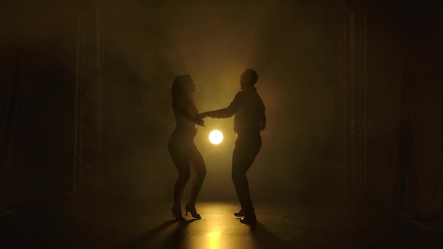 Young couple dancing latin music. Bachata, merengue, salsa. Shot in a dark studio with neon lights in the background.