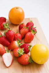 Fototapeta na wymiar strawberries and oranges on cutting board