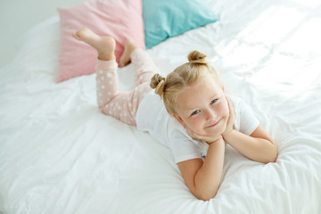 Fototapeta premium Little girl in bed with white linen. A child at home in the morning wakes up in his room. High quality photo.