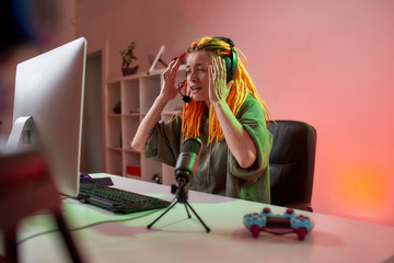 Oh no. Female esport gamer, woman in headphones looking emotional, playing online video game on PC while recording, filming vlog at home