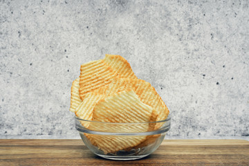 Fototapeta premium Corrugated potato chips on a wooden board. Snack, junk food. Close up.